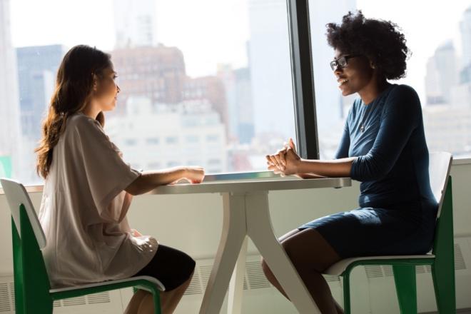 two women talking by a sunny window